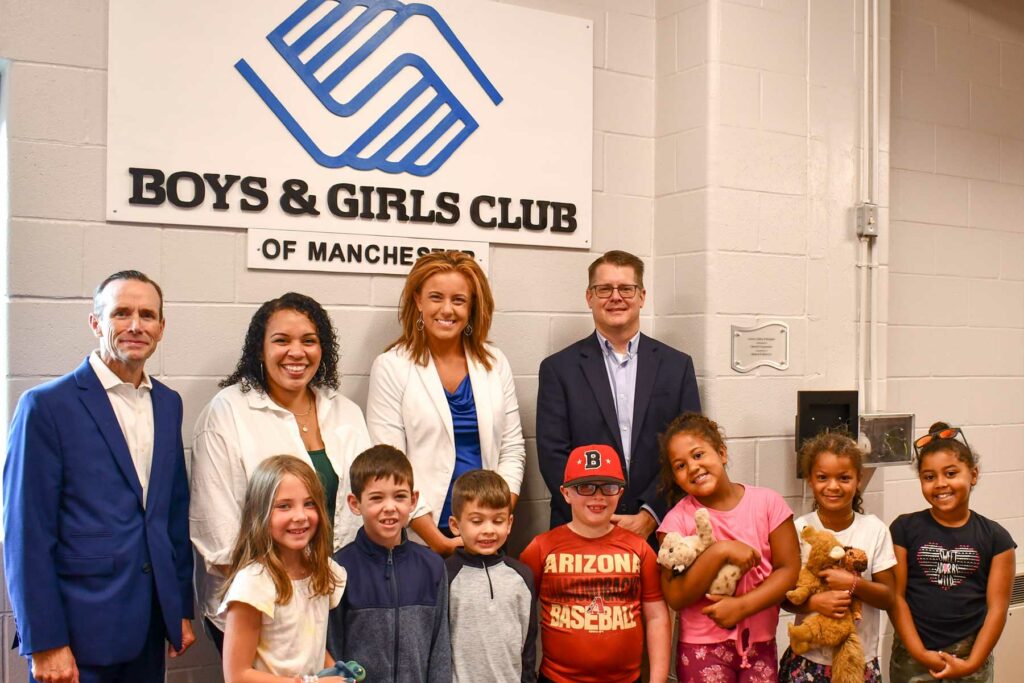 staff and kids in front of logo